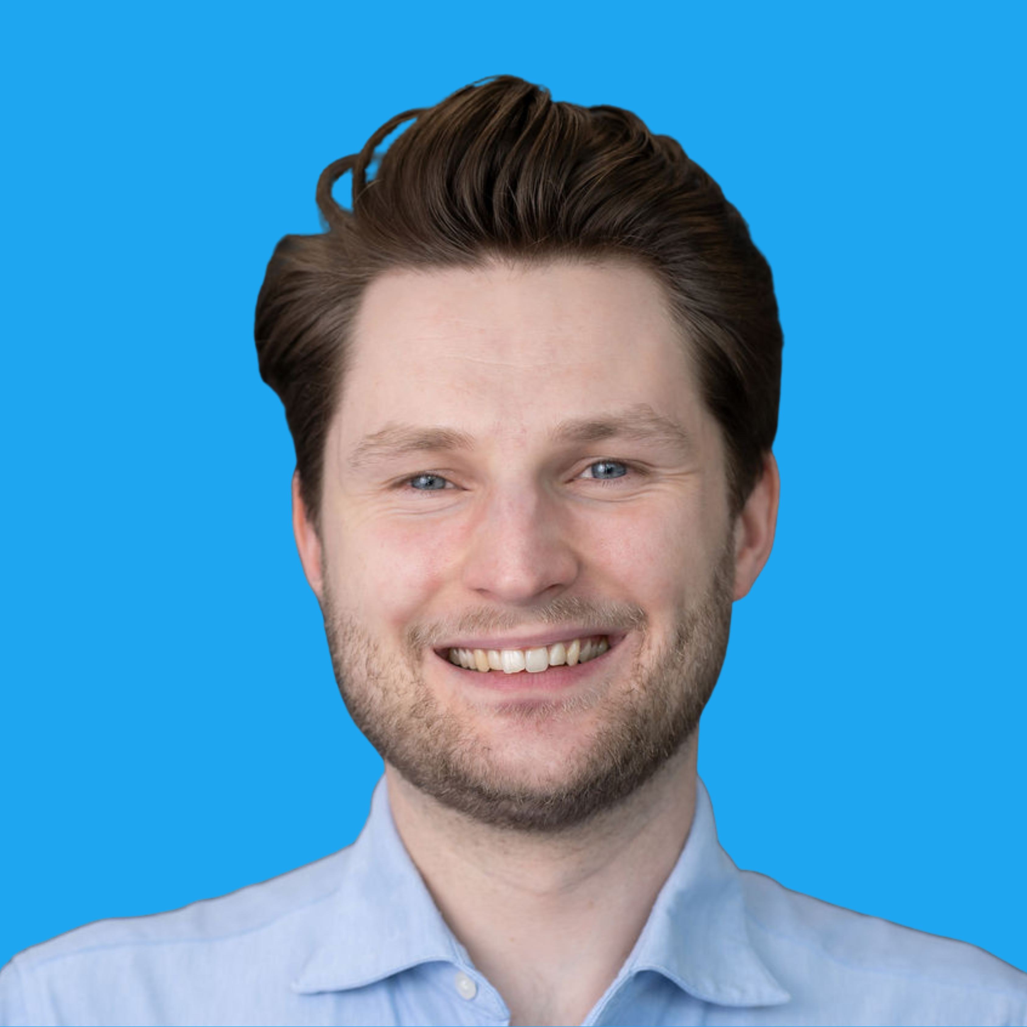 Smiling man with brown hair and beard wearing light blue shirt against bright blue background
