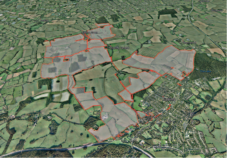 Aerial view of countryside with agricultural fields, green vegetation, and red boundary lines marking property divisions across rural landscape.
