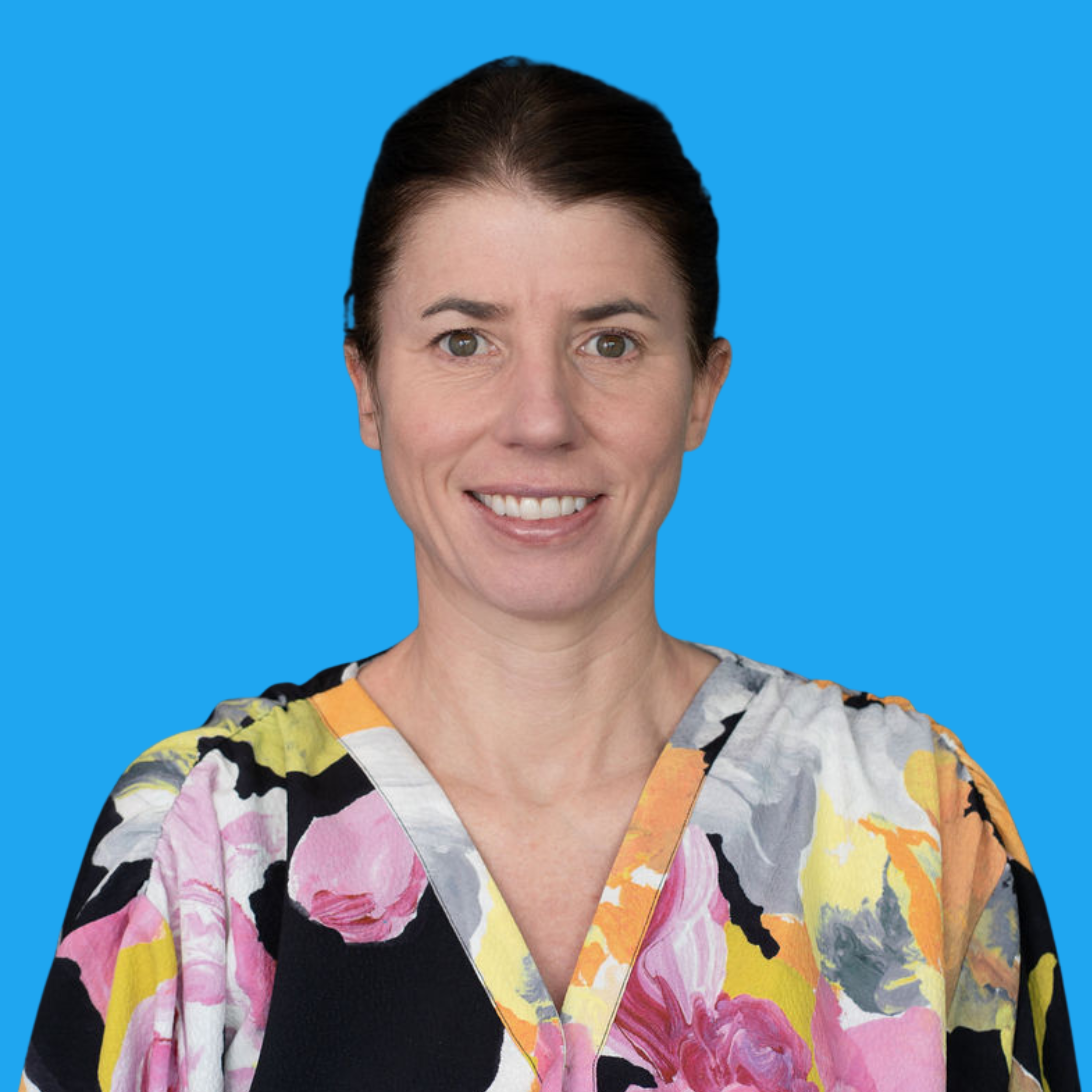 Woman with brown hair tied back, smiling, wearing colourful floral top with pink, yellow, orange and black patterns against blue background